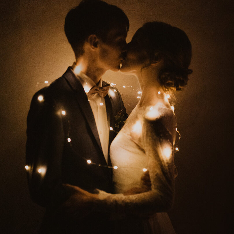 Paar küsst sich und ist eingewickelt in eine Lichterkette