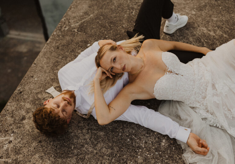 Braut und Bräutigam liegen am Boden beim Afterweddingshooting