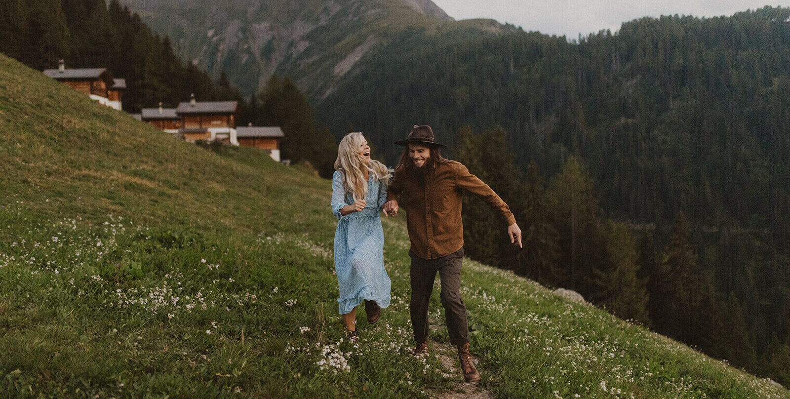 Paar springt auf einem Weg in den Walliser Bergen.