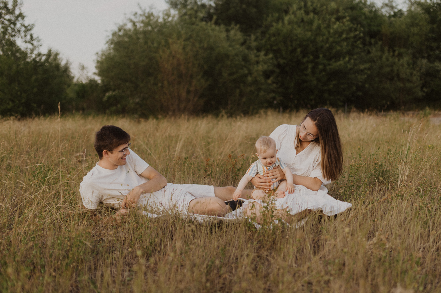 Familie sitzt am Boden im Gras mit ihrem Kind. In Olten.