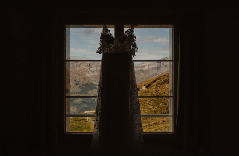 Hochzeitskleid hängt an einem Fenster im Berghaus auf dem Jochpass.