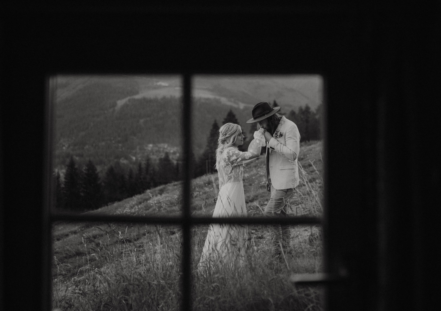 Foto durch ein Fenster von einer Braut und einem Bräutigam in den Schweizer Bergen an ihrem Elopement
