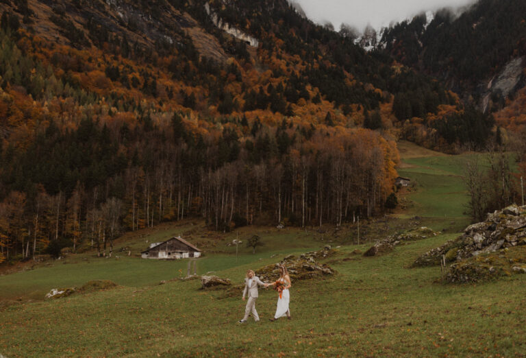 Hochzeitspaar in den Schweizer Bergen am Hochzeitsfotos machen im Herbst. Sie laufen über eine Wiese