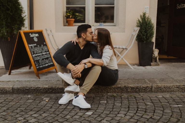Paar sitzt in Aarau in der Altstadt am Boden und küsst sich.