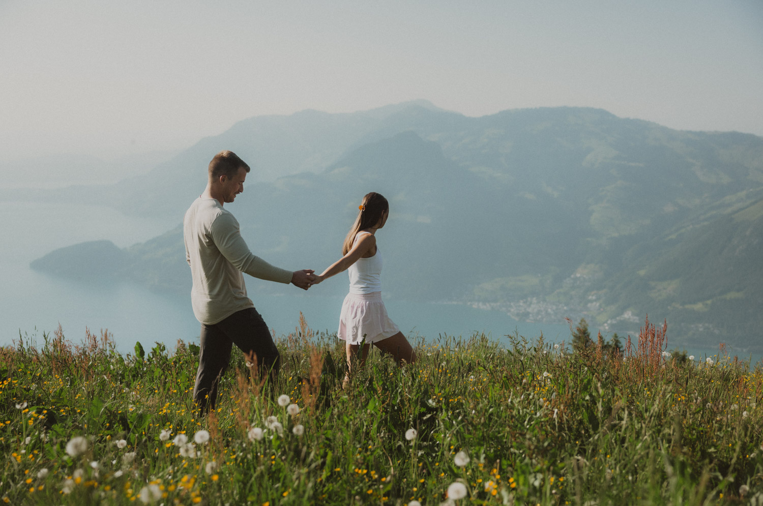 lucerne-proposal-photography walking in a meadow at the proposal photography session in lucerne with mountains in the background