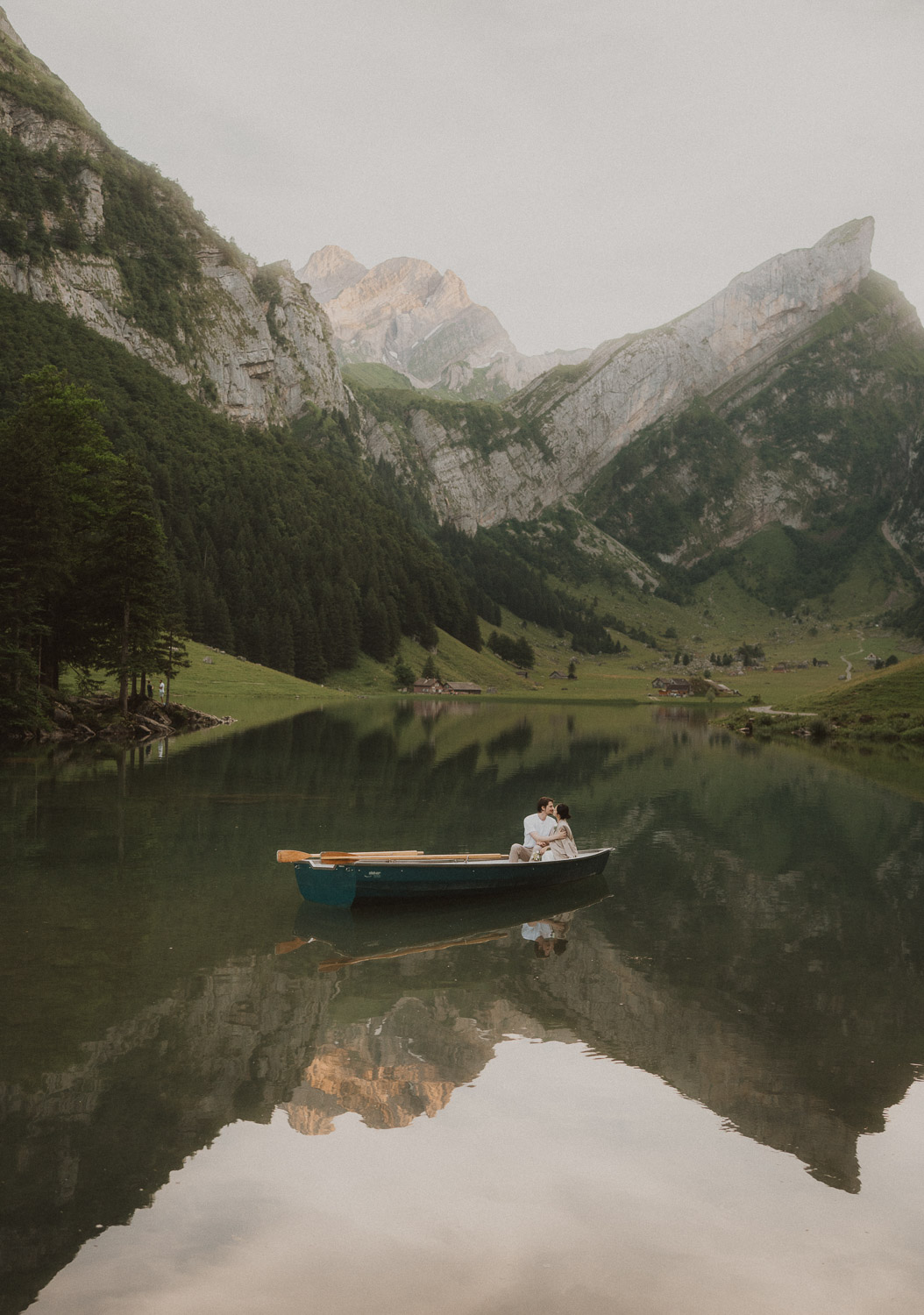 Couple eloping and kissing in a row boat at Seealpsee in Appenzell, photographed by an elopement and proposal photographer.
