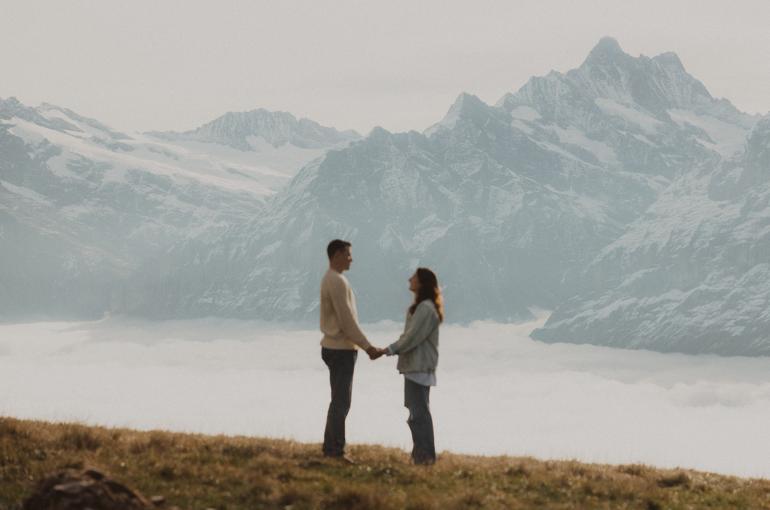 Couple at a surprise proposal photography session holding hands in the Jungfrauregion with alpine mountain scenery and natural outdoor setting in daylight.
