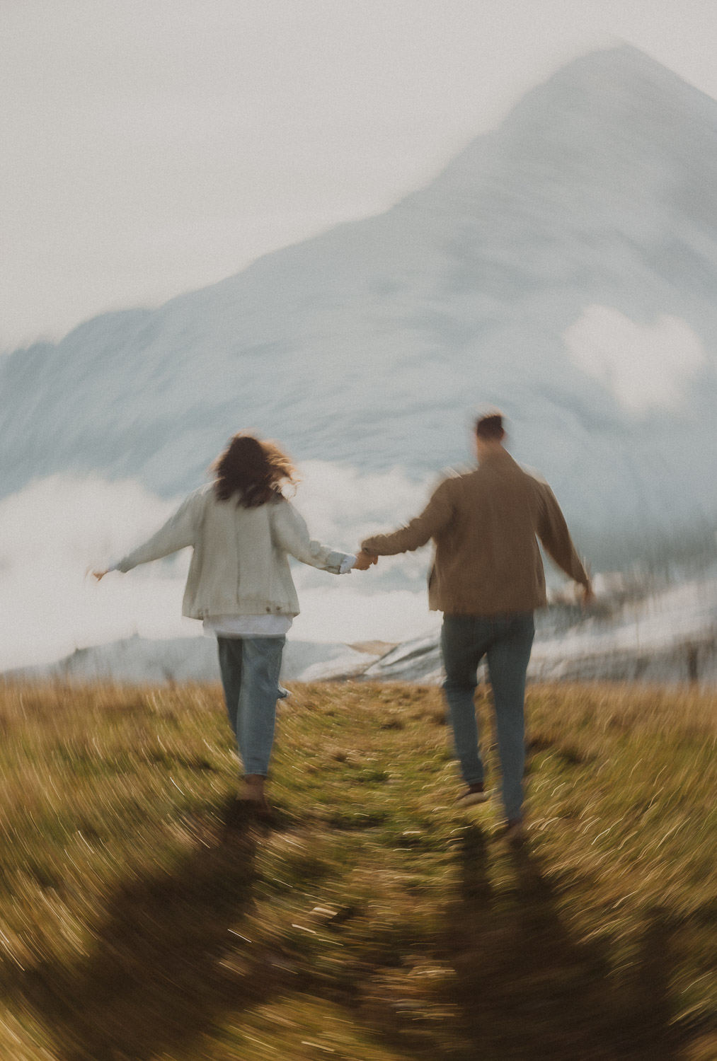 Couple running at a surprise proposal photography session in the Jungfrauregion with alpine mountain scenery and natural outdoor setting in daylight.