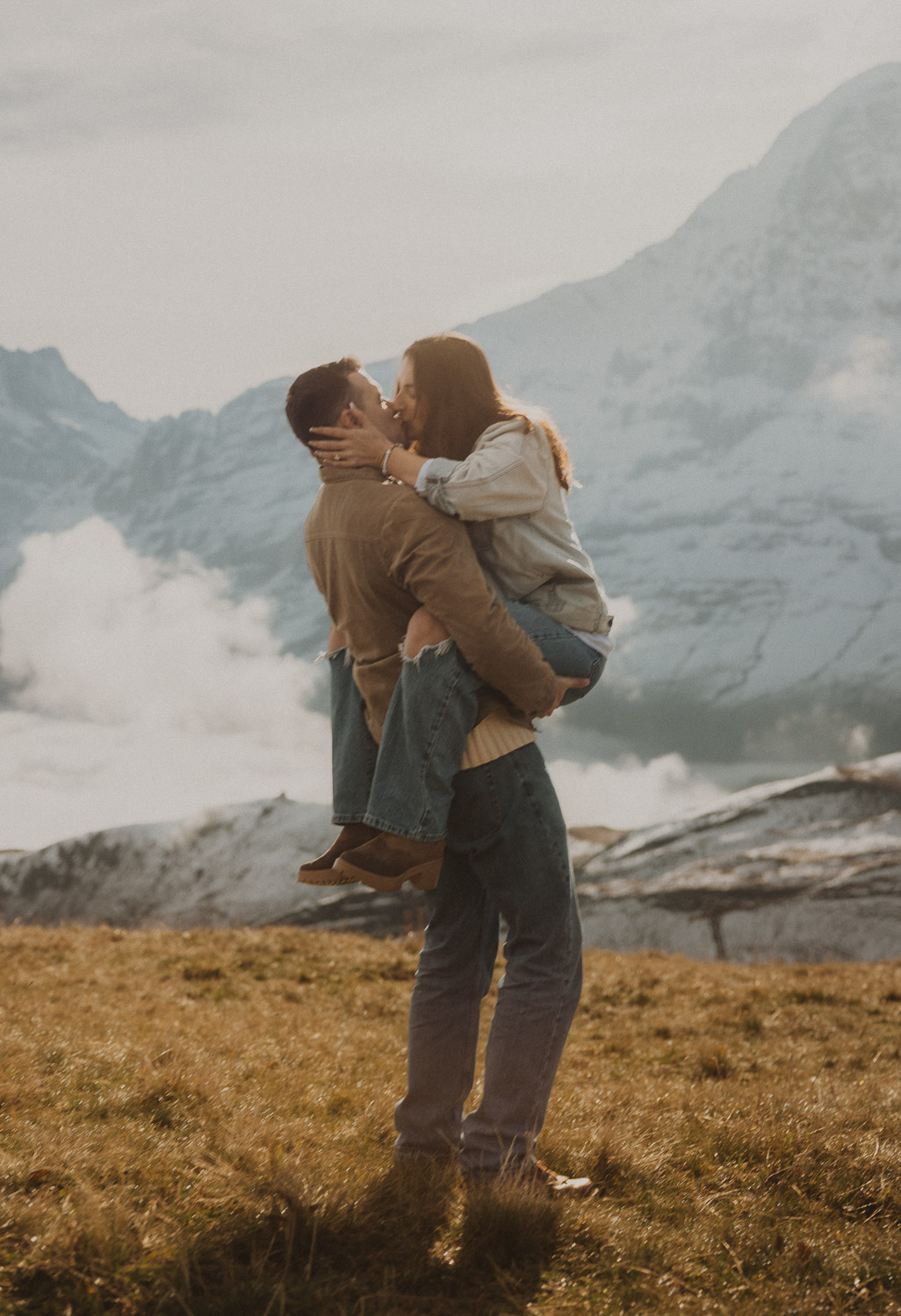Couple kissing at a surprise proposal photography session in the Jungfrauregion with alpine mountain scenery and natural outdoor setting in daylight.