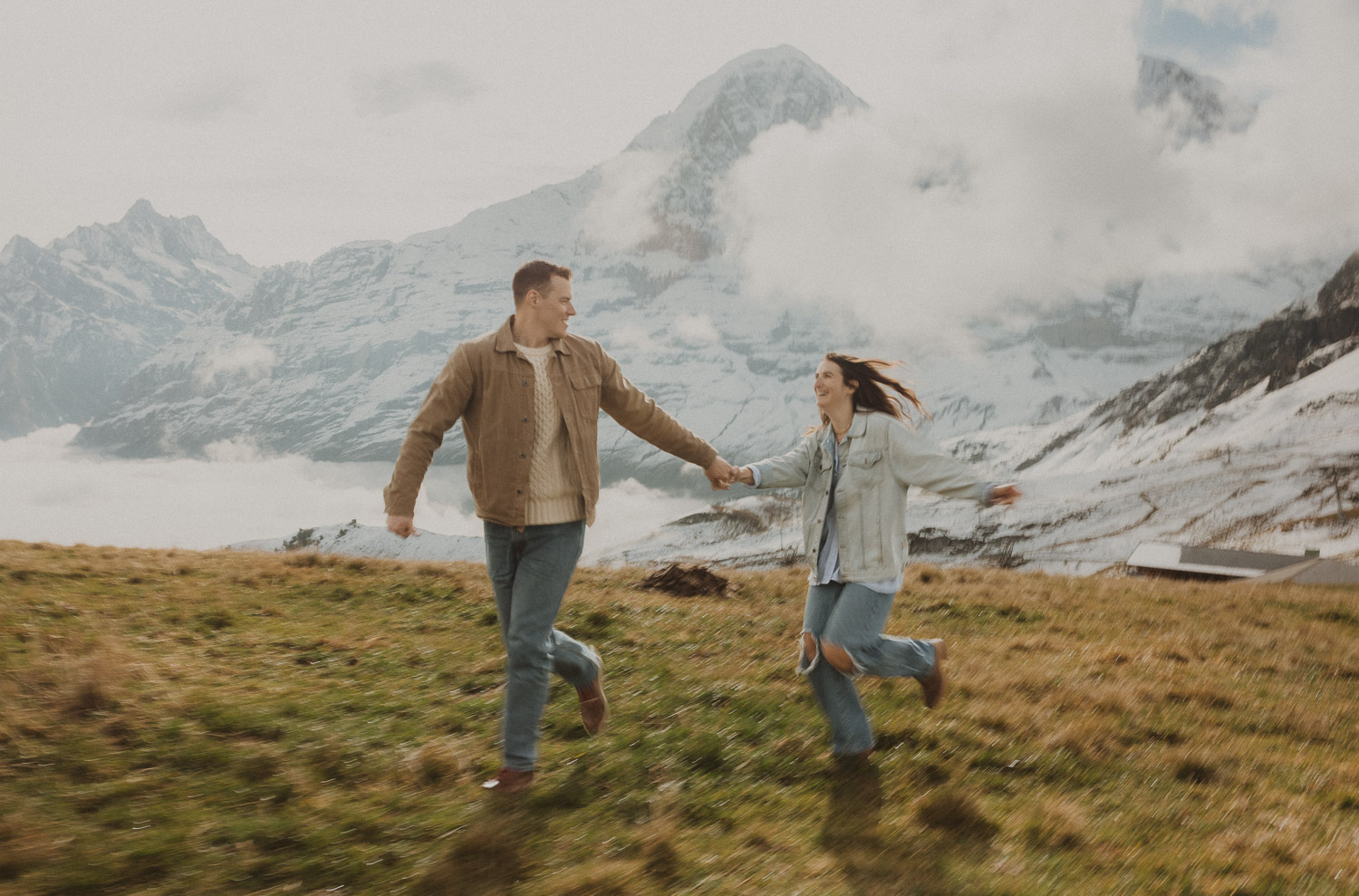 Couple running at a surprise proposal photography session in the Jungfrauregion with alpine mountain scenery and natural outdoor setting in daylight.