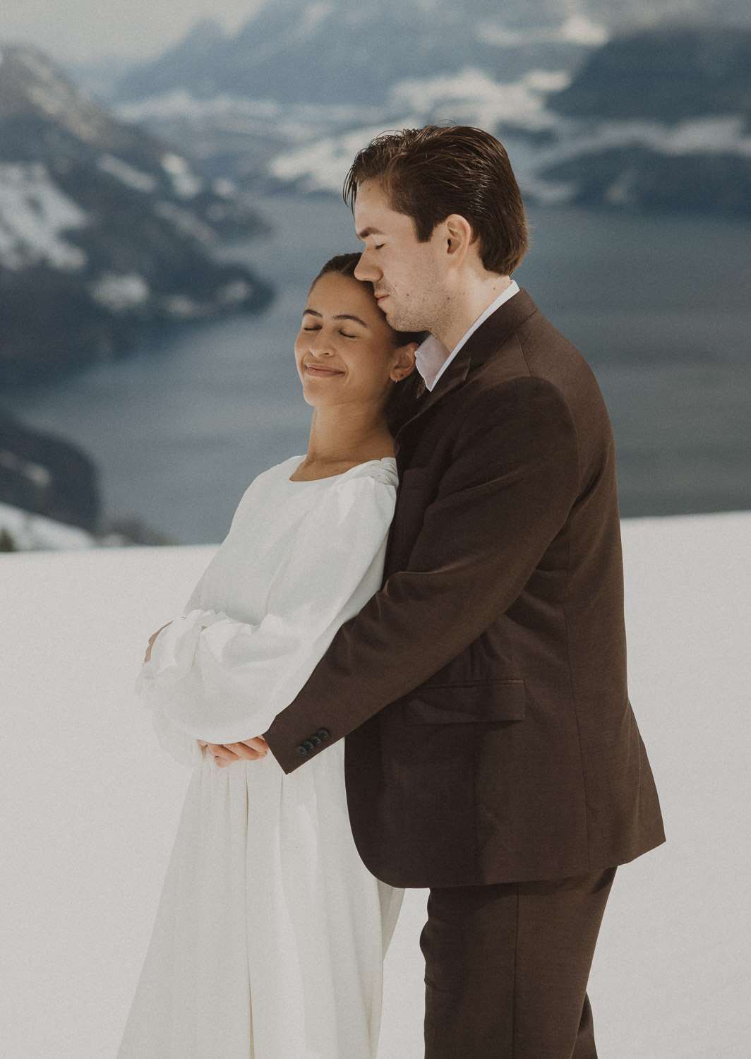 Couple during an elopement photography session in Lucerne with snow-covered alpine mountains and a lakeside backdrop.