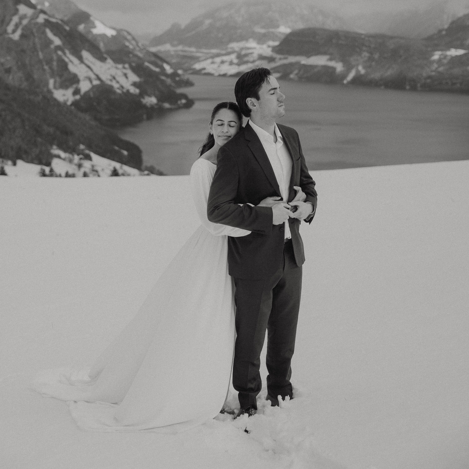 Couple during an elopement photography session in Lucerne with snow-covered alpine mountains and a lakeside backdrop.