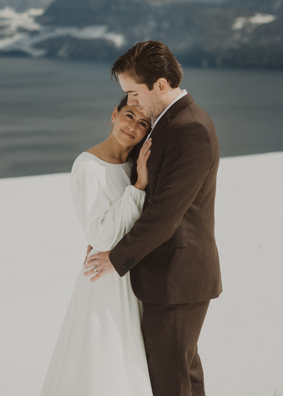 Couple during an elopement photography session in Lucerne with snow-covered alpine mountains and a lakeside backdrop.