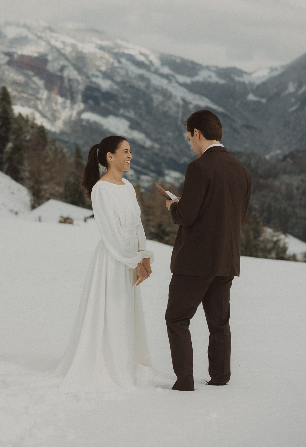 Couple exchanging vows on an elopement photography session in Lucerne with snow-covered alpine mountains and a lakeside backdrop.