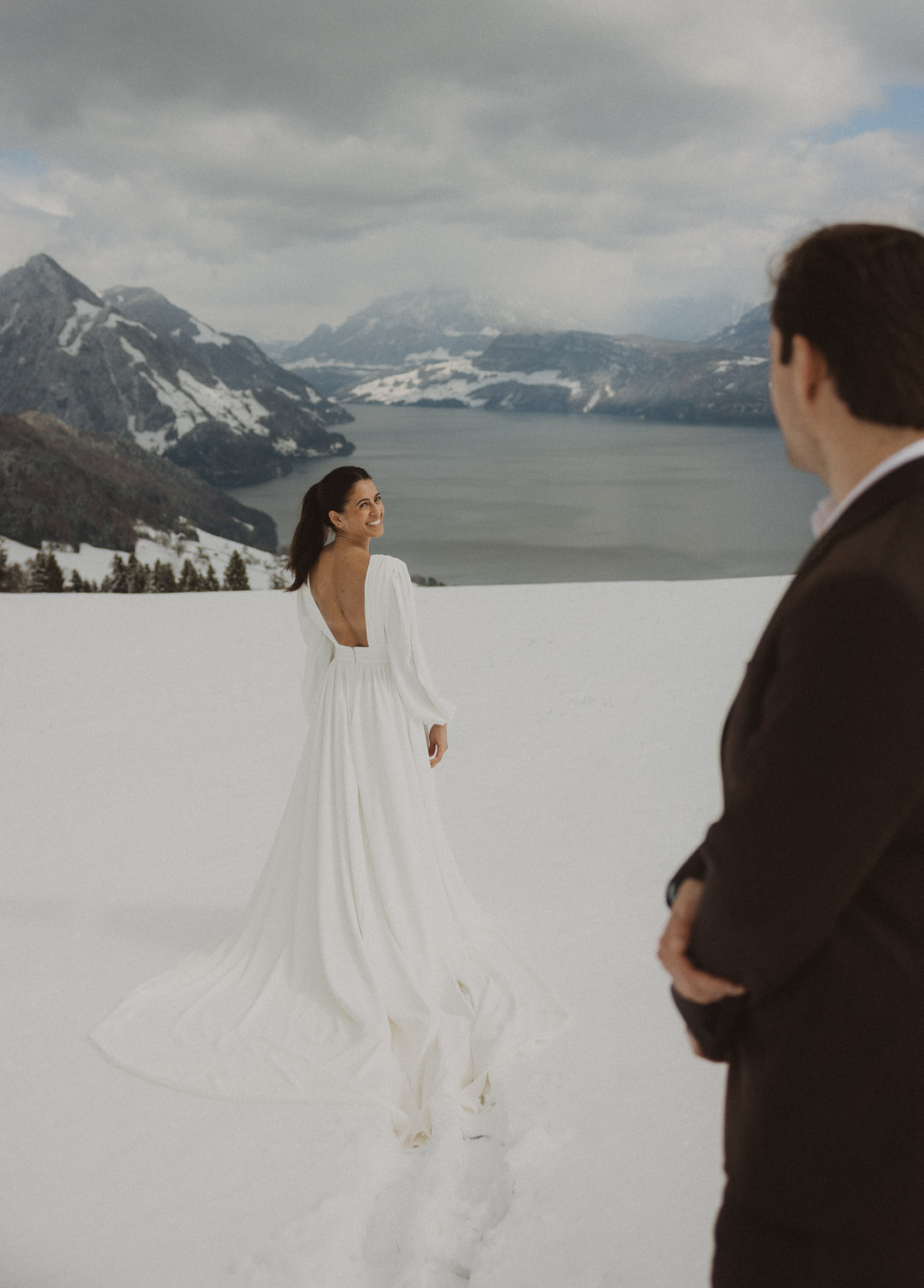 Couple during an elopement photography session in Lucerne with snow-covered alpine mountains and a lakeside backdrop.