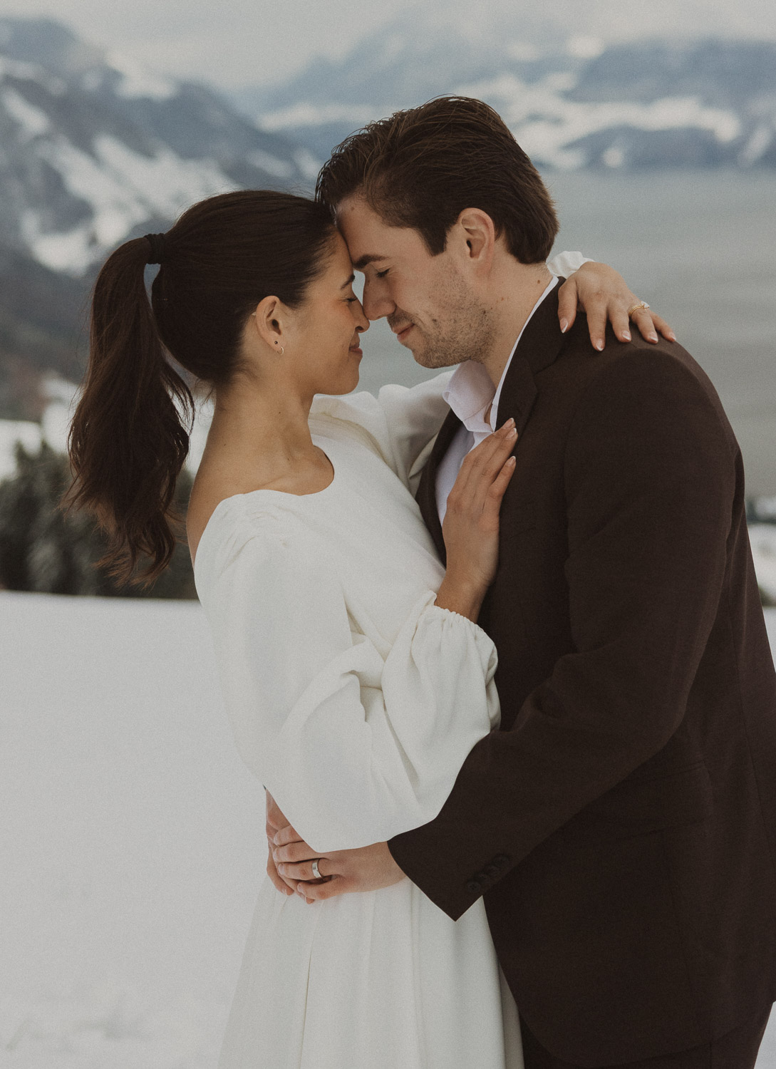 Couple during an elopement photography session in Lucerne with snow-covered alpine mountains and a lakeside backdrop.