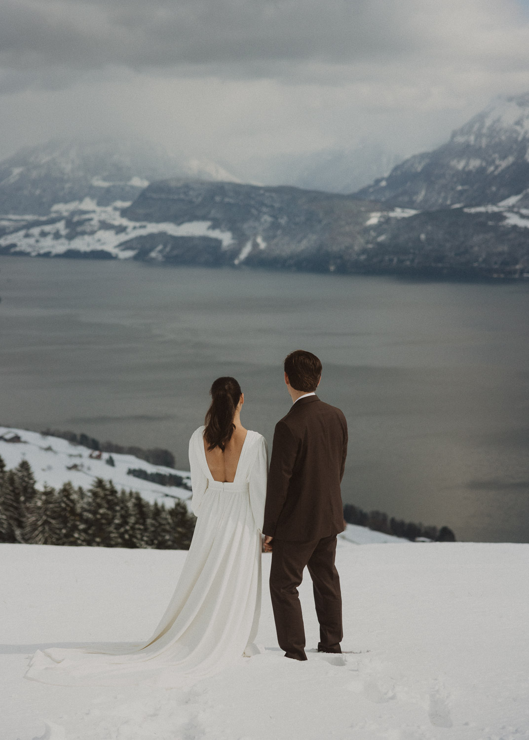 Couple during an elopement photography session in Lucerne with snow-covered alpine mountains and a lakeside backdrop.