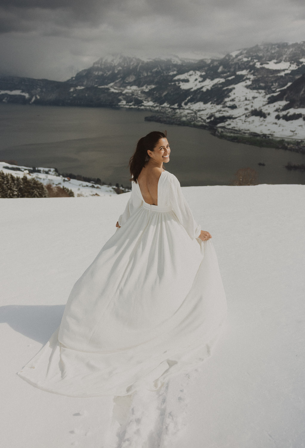 Bride during an elopement photography session in Lucerne with snow-covered alpine mountains and a lakeside backdrop.